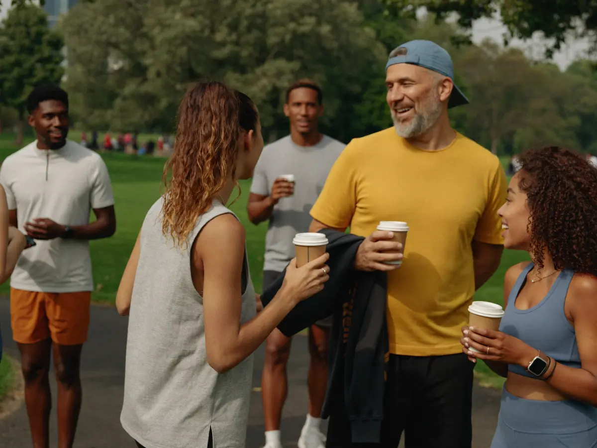 A running club laughing together over coffee after a morning run