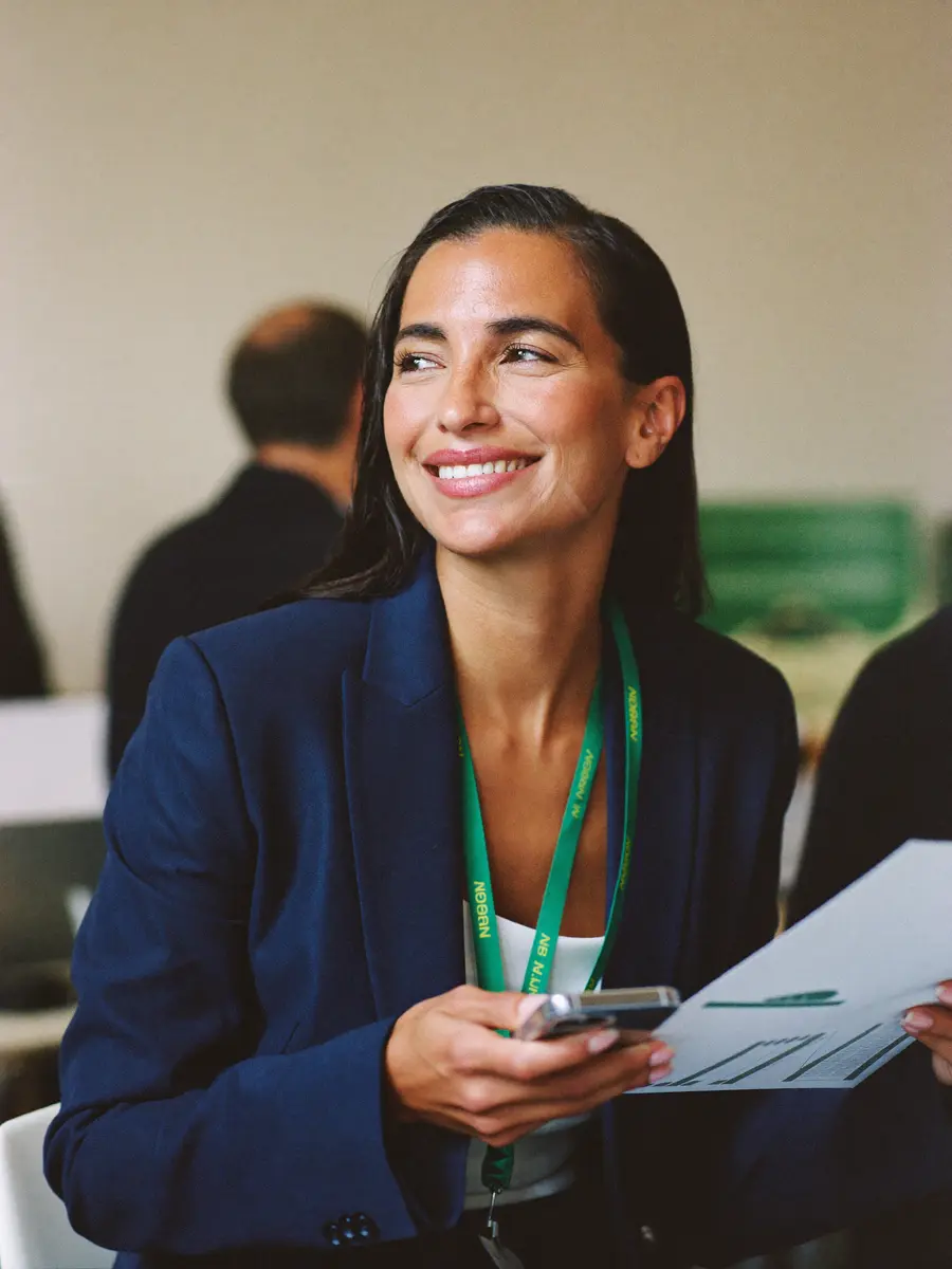 An association member at a conference, smiling at her phone