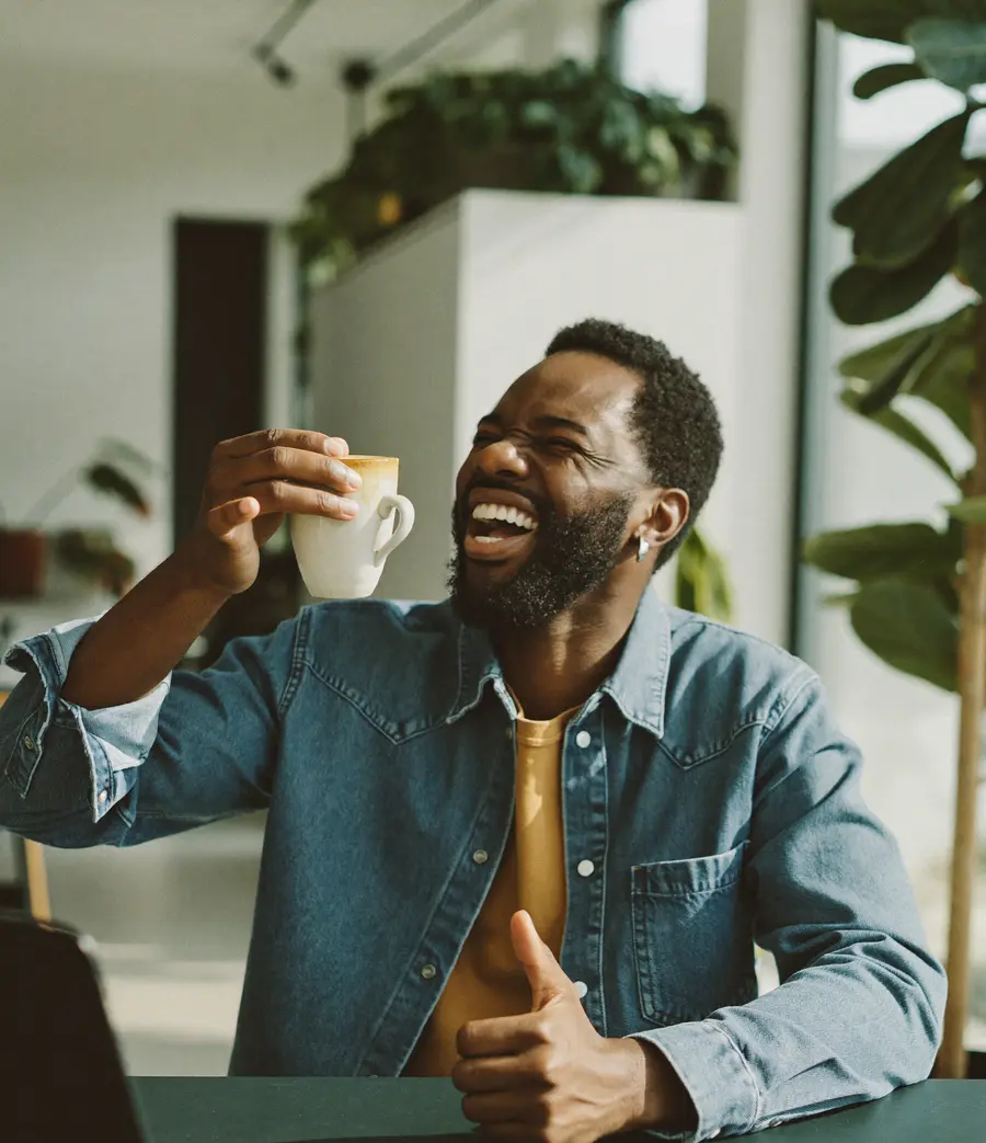 A small business owner laughing over coffee in a coworking space